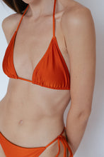 Close-up view of model wearing Sinclair Bikini Top in Shimmer Burnt Orange by Ozero Swimwear, front view, designed in Malaysia.