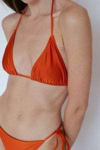 Close-up view of model wearing Sinclair Bikini Top in Shimmer Burnt Orange by Ozero Swimwear, front view, designed in Malaysia.